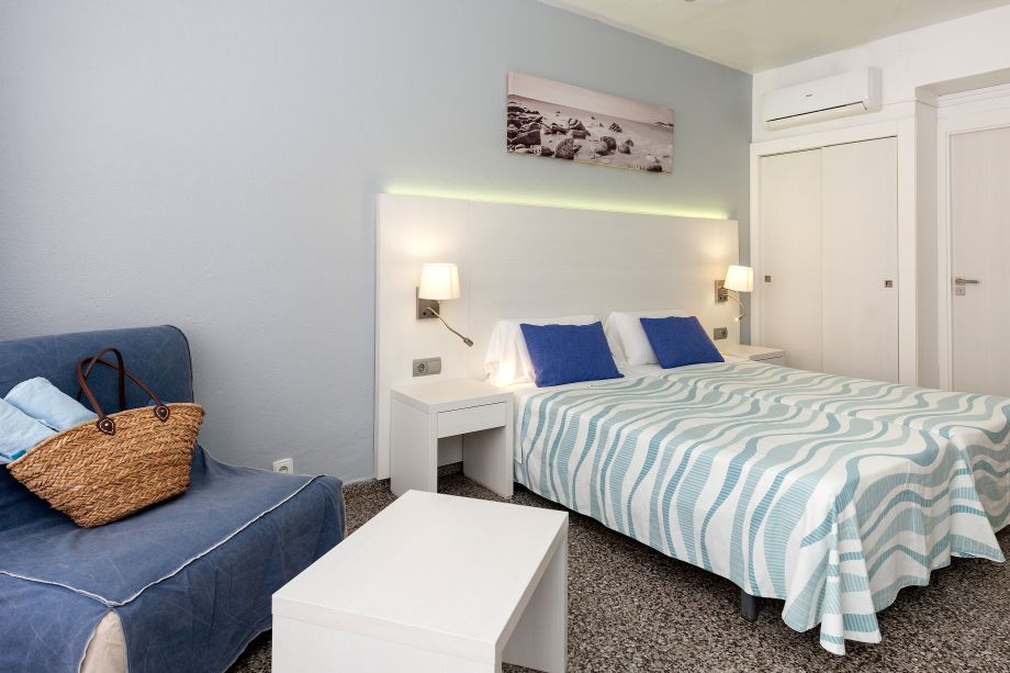 Detalle del sillón, mesa auxiliar y cama en habitación doble de Hostal Pitiusa Ibiza
